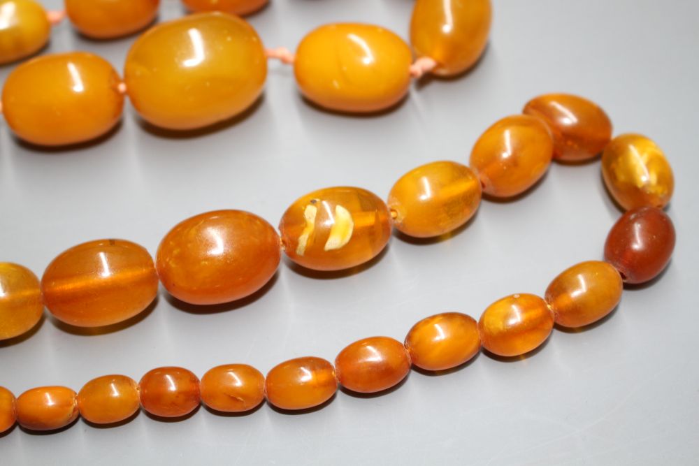 Two single strand graduated oval amber bead necklaces, with yellow metal clasps, one stamped 375,